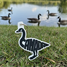 Load image into Gallery viewer, Keychain with a goose design and 'Canada' text on a textured gray surface
