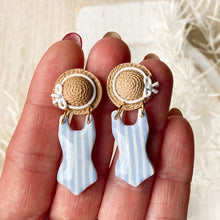 Load image into Gallery viewer, Earrings with straw hat and swimsuit design held between fingers against a neutral background
